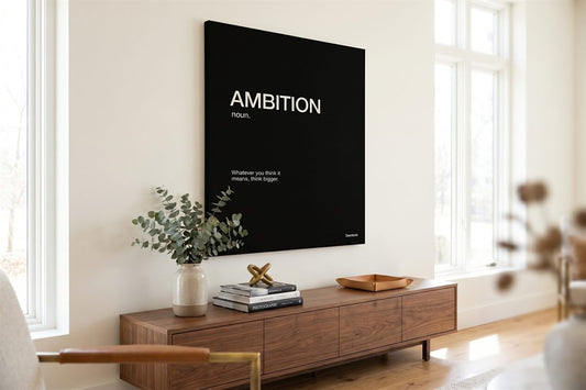 Black and white canvas art: an Ambition monochrome print above a walnut console with eucalyptus in a bright living room