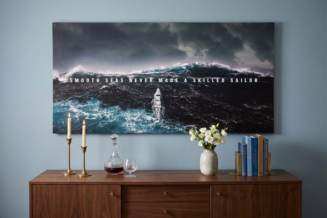 Dining room wall art: a Smooth Seas seascape canvas above a walnut sideboard with brass candlesticks in a blue dining room