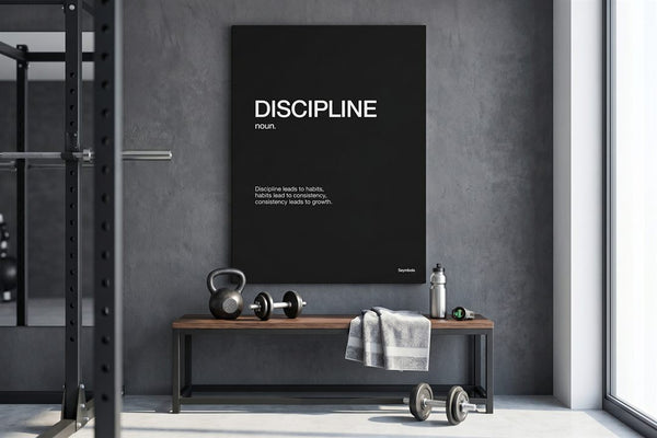 Home gym wall art: a Discipline definition canvas on a concrete wall above a bench with a kettlebell and dumbbells