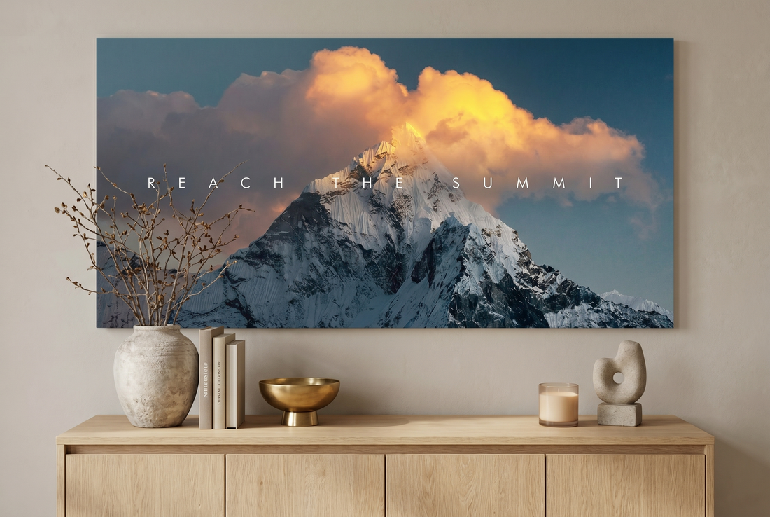 Landscape wall art: a Reach The Summit mountain canvas above an oak sideboard with a vase and books
