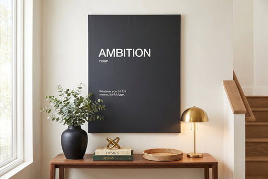 Staircase wall art: an Ambition definition canvas on a bright landing with a console, eucalyptus and books
