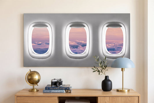 Travel wall art: an aerial window-seat canvas in a bright living room with a globe and a vintage camera