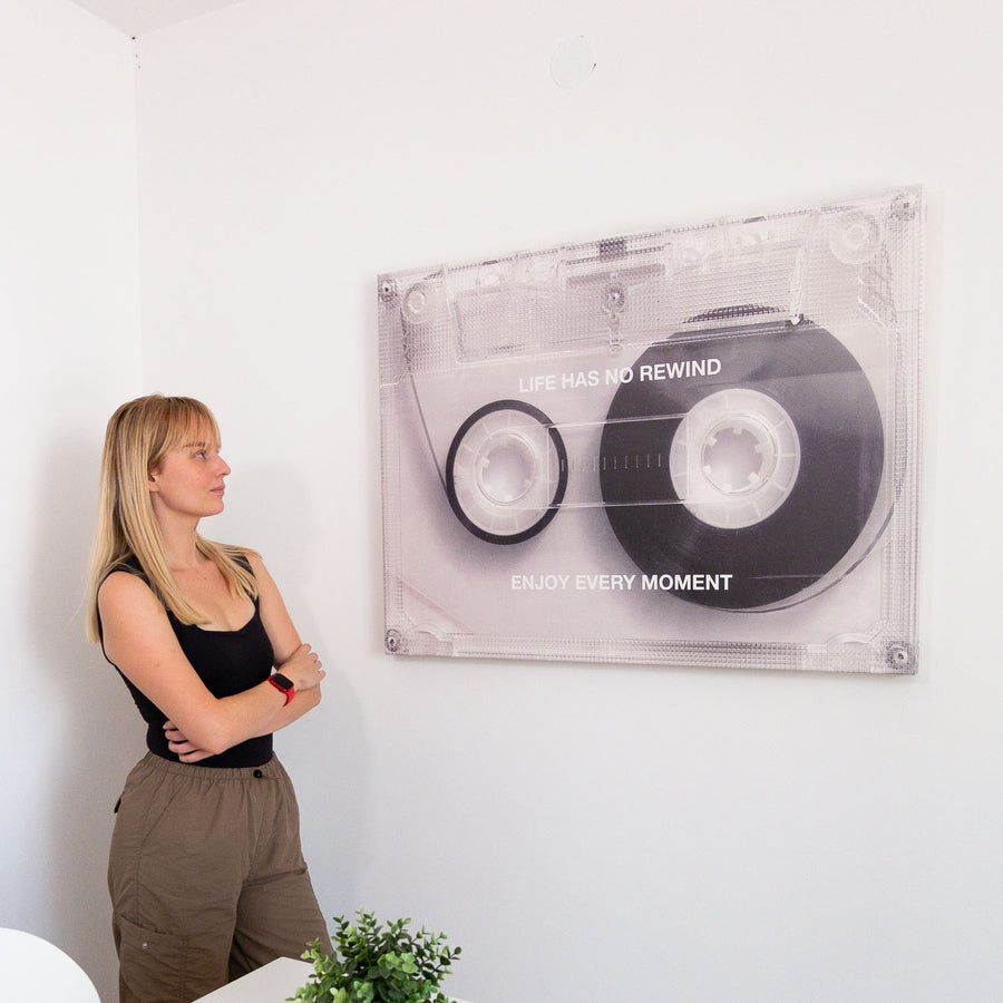 Woman standing next to a wall with a large cassette tape Seembols canvas art  featuring text No Rewind Enjoy Every Moment