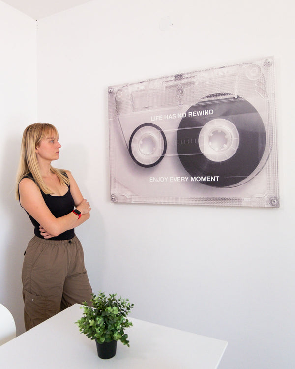 Woman standing next to a wall with a large tape cassette canvas art featuring inspirational quote.