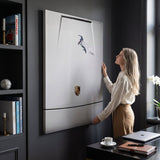 Woman straightening the Car Boarding canvas on a charcoal study wall beside a desk and ski travel books