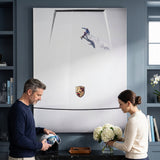 Couple below the Car Boarding canvas in a slate blue room, he holds a ski helmet and she arranges white hydrangeas