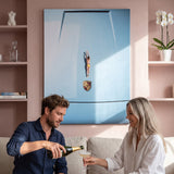 Couple pouring champagne beneath the Car Dive canvas in a blush pink living room