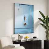 Car Dive canvas above a black sideboard with a champagne bucket and lemons in a bright pool house room