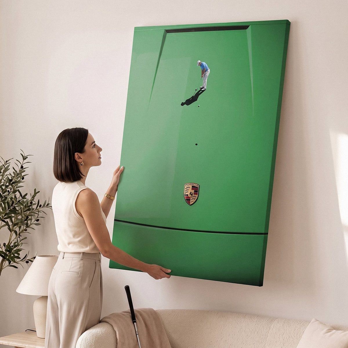 Woman hanging the Car Putt canvas in a cream living room with a putter leaning against the sofa
