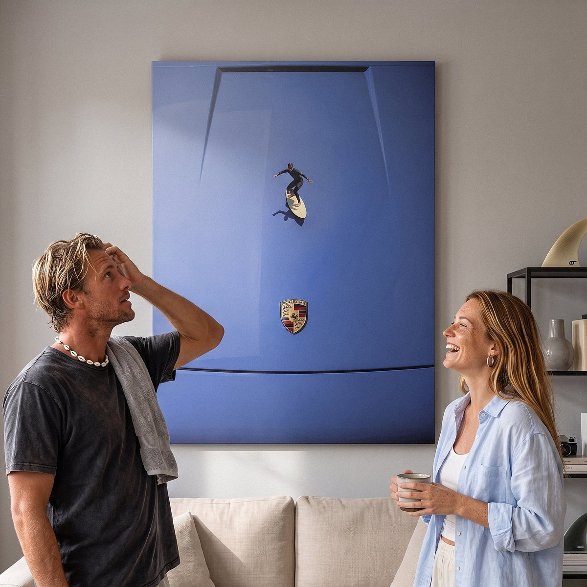 Surf couple back from the water laughing below the Car Surfing canvas in a stone gray living room