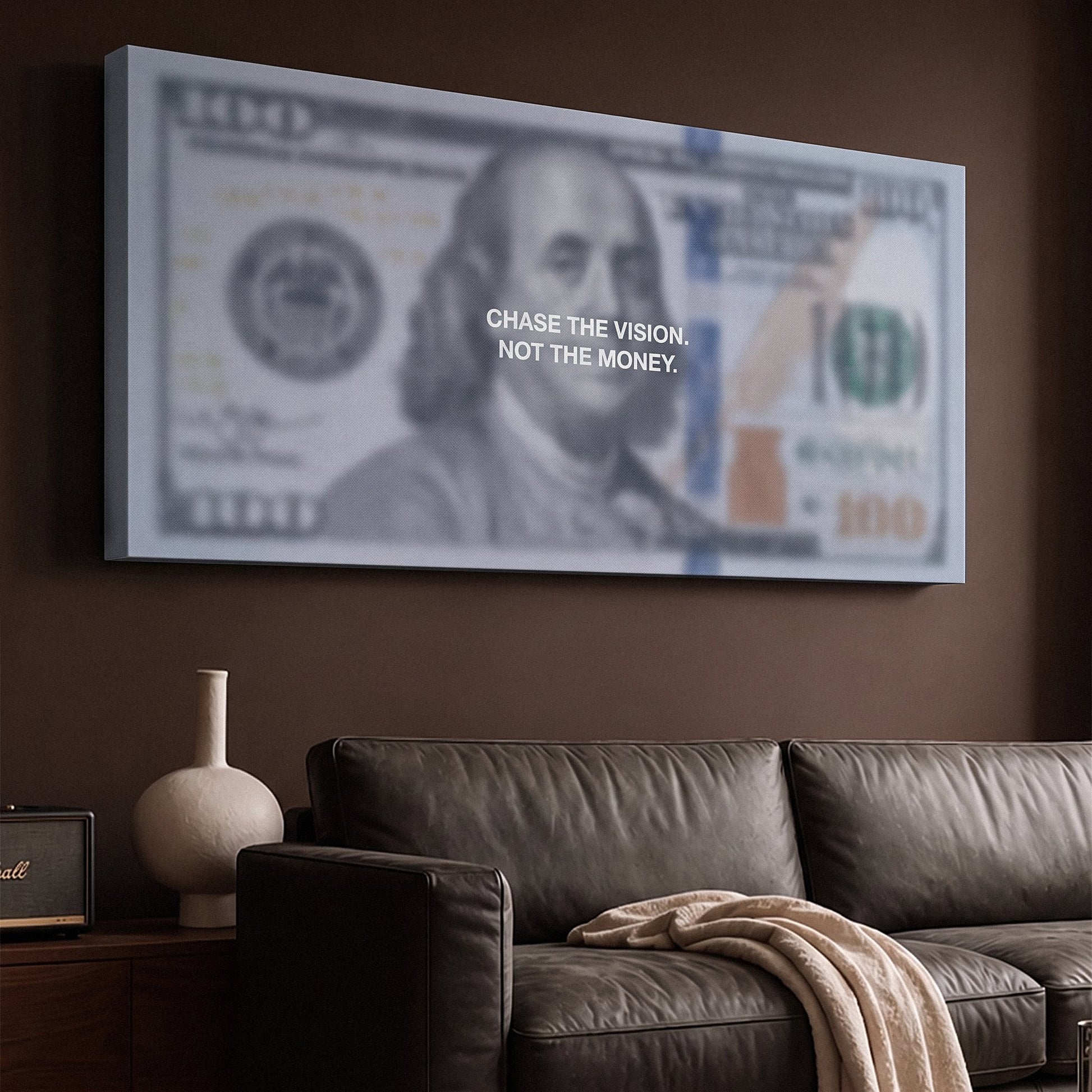 Chase The Vision Dollar Edition money canvas on a brown living room wall above a black leather sofa