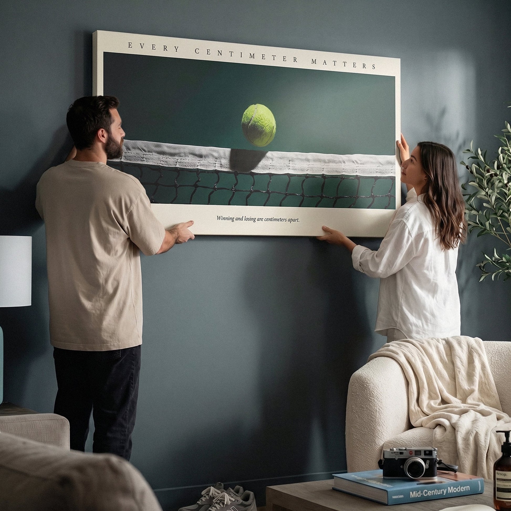 Two people holding the Every Centimeter Matters tennis panoramic canvas print in a living room