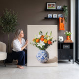 Woman kneeling beside the Football Vase canvas leaning against a taupe wall