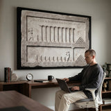 Man working at a laptop below the Inches Apart marble canvas in a home office