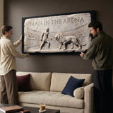 Two men hanging the Man In The Arena marble relief canvas above a sofa