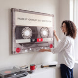 Person working at a desk below the Pause If You Must clear cassette canvas