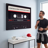 Person working at a desk below the Press Play black cassette canvas