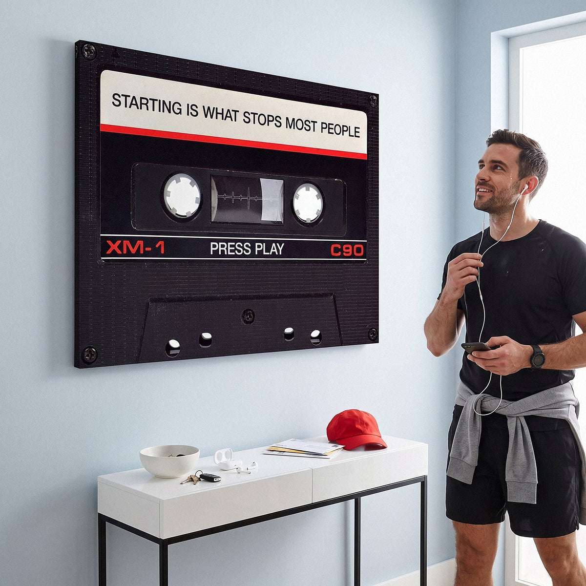 Person working at a desk below the Press Play black cassette canvas