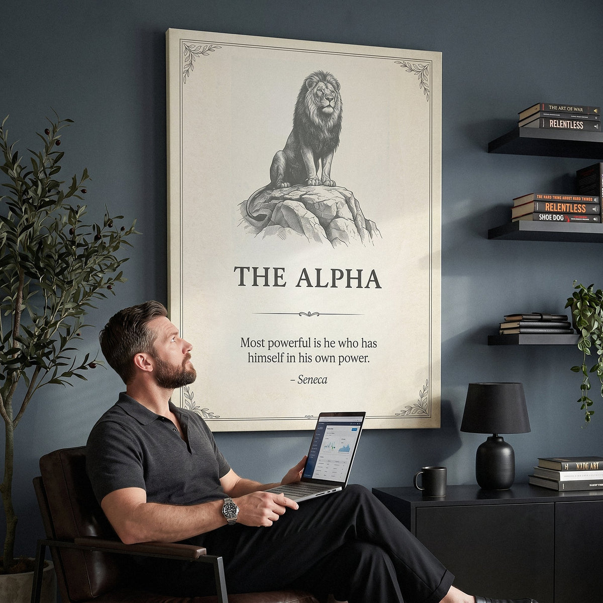 Man in a leather chair with a laptop looking up at The Alpha lion quote canvas