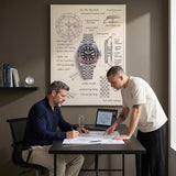 Two men reviewing watch movement drawings under The Meridian Design blueprint canvas