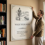 Man hanging the Walk Your Path quote canvas beside a bookshelf